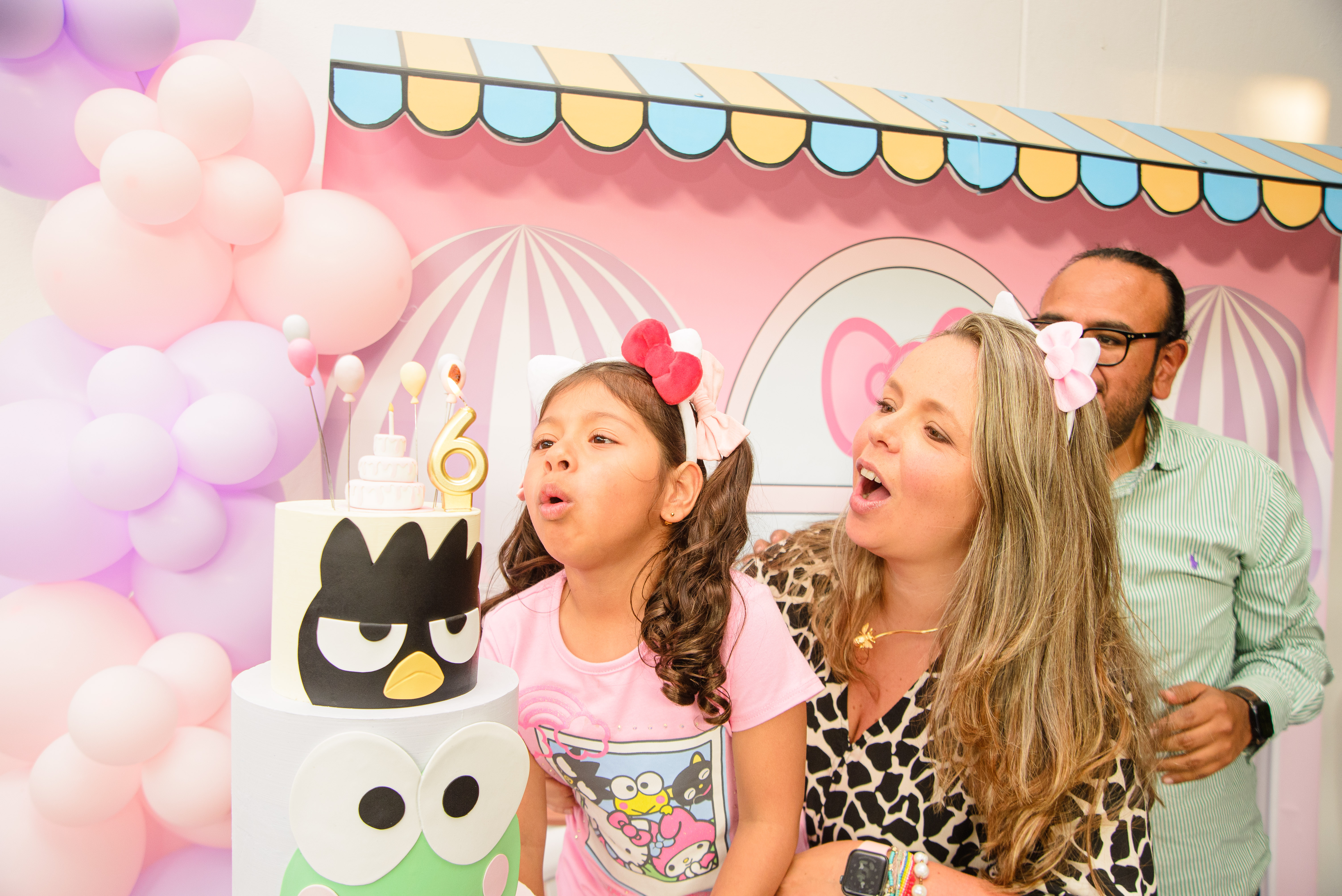 Cumpleaños infantil con pastel y decoración temática en Diversitopia; niña soplando velas acompañada de su familia.